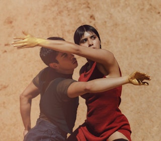 Two dancers pose dramatically against an earthy background.
